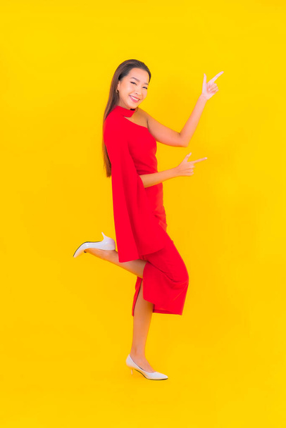 Portret piękna młoda azjatycka kobieta uśmiech z akcji na żółtym odizolowanym tle - Zdjęcie, obraz