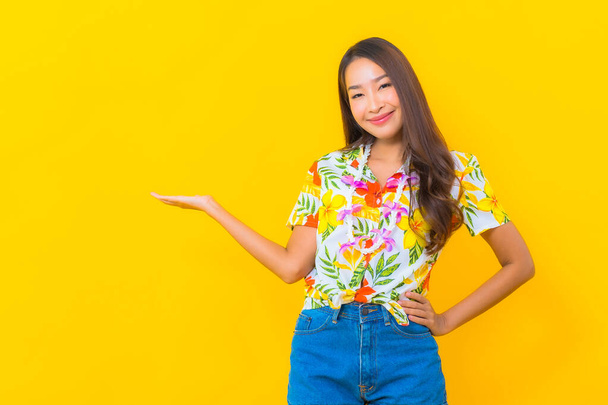 Portrait beautiful young asian woman wear colorful shirt on yellow background for sonkran festival in Thailand - Photo, Image