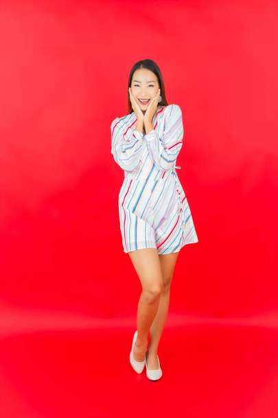 Portré gyönyörű fiatal ázsiai nő mosoly sok akció a piros háttér - Fotó, kép