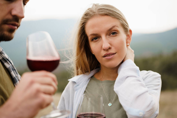 Smiling couple toasting wine glasses outdoors in mountains - Foto, Bild