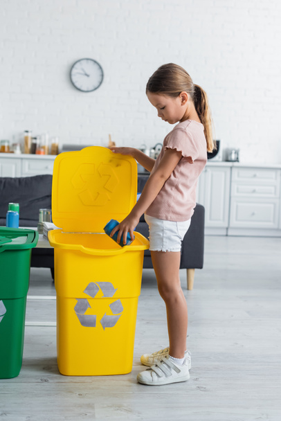 Oldalnézet a gyermek dobja szemetet szemetesbe újrahasznosítás felirat otthon  - Fotó, kép