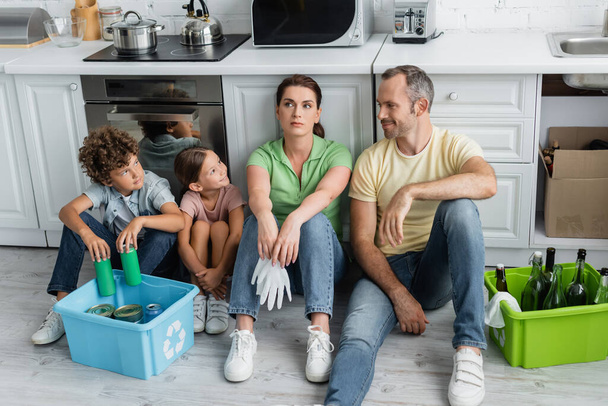 Smiling father looking at kids near trash in boxes in kitchen  - Photo, Image