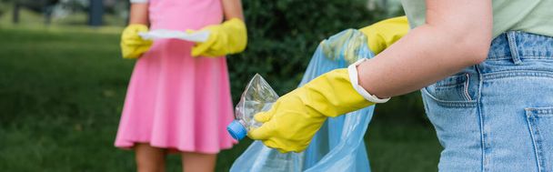Cropped view of mother holding trash bag near daughter with garbage outdoors, banner  - Foto, Bild