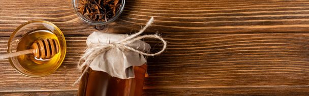 vista superior do frasco de mel coberto com papel artesanal perto de tigelas com dipper e sementes de anis na mesa de madeira, banner - Foto, Imagem