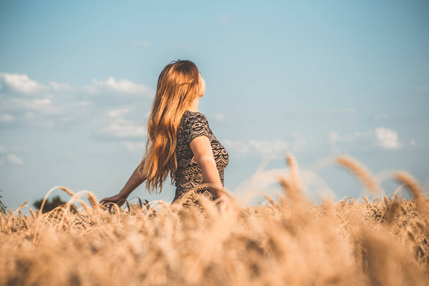 happy romantic young woman enjoying nature, raising hands on background of cloudy sky in wheat field, girl breathe breathes deeply , freedom and relaxation concept - Photo, Image