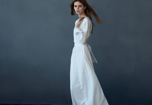 Nainen valkoisessa mekossa poseeraa tummalla taustalla. Laadukas kuva - Valokuva, kuva