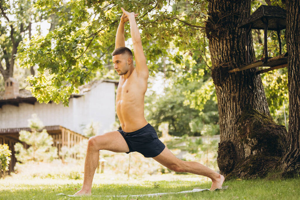 Portrait complet de jeune homme beau pratiquant le yoga à l'extérieur lors d'une chaude journée d'été - Photo, image