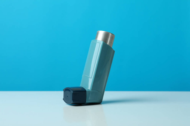 Inhalador de asma sobre mesa blanca sobre fondo azul - Foto, Imagen