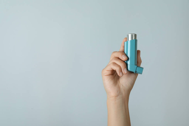 Female hand holds asthma inhaler on light gray background - Zdjęcie, obraz