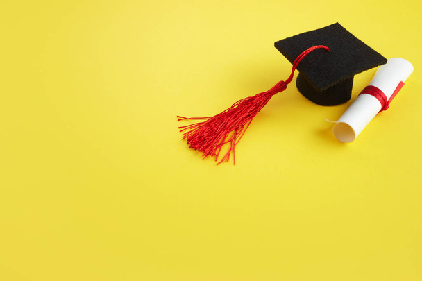 Academic hat with diploma on yellow background. Graduation theme - Zdjęcie, obraz