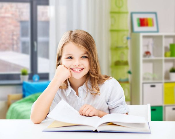 happy smiling student girl reading book at home - Фото, изображение