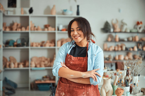 Ceramista feminina alegre em pé na oficina de cerâmica - Foto, Imagem