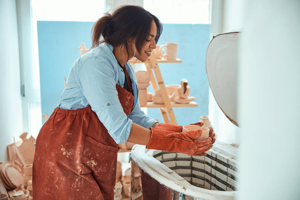 Okouzlující ženské hrnčíř pomocí elektrické keramiky pece v dílně - Fotografie, Obrázek