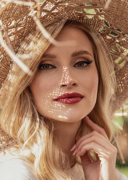 Close up portrait of beautiful young woman wearing fashionable straw hat enjoying her summer holidays. Beauty blonde lady with glamour makeup and red lips looking at the camera. Real people lifestyle concept - Fotografie, Obrázek
