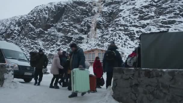 Murmansk region, Russia - January 10, 2021: A group of tourists arrived by cars on winter vacation and go with suitcases to the hotel - Footage, Video