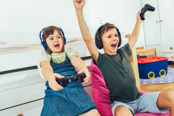 glückliche Kinder - Mädchen und Junge spielen ein Videospiel - Foto, Bild