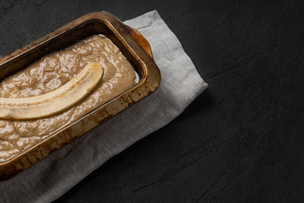Raw banana bread dough in rectangular baking dish on black background - Photo, image
