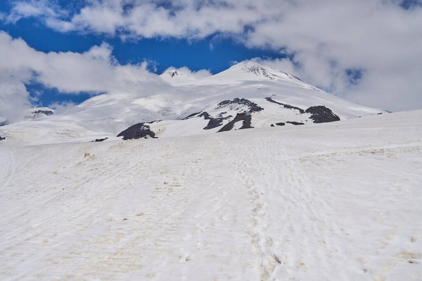 Снігові вершини яскравого сонця і білих хмар над вершинами Кавказьких гір. - Фото, зображення