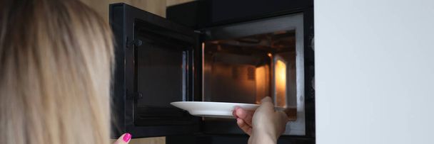 Donna che mette il piatto di cibo nel forno a microonde a casa primo piano - Foto, immagini