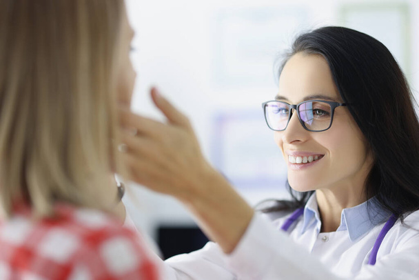 Жінка-лікар в окулярах вивчає пацієнтські підмандатні лімфатичні вузли в клініці
 - Фото, зображення