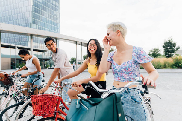 Group multiethnic friends posing outdoor riding bicycle enjoying sustainable alternative transportation - Fotó, kép