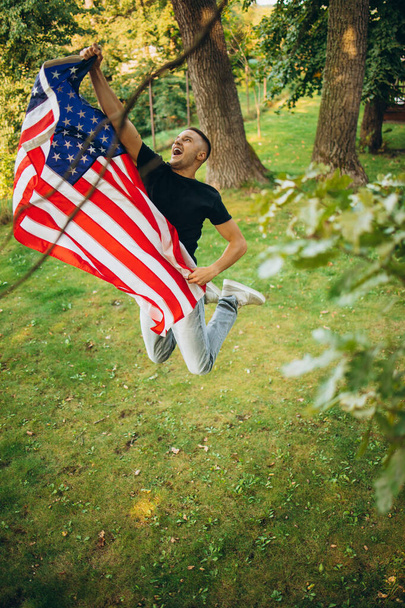 Top view portret młodego przystojnego mężczyzny trzymającego flagę Ameryki - Zdjęcie, obraz