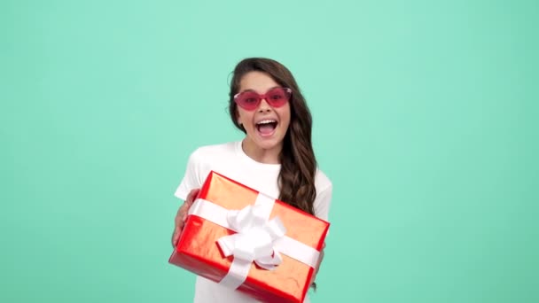 Güneş gözlüklü hayret bir çocuk doğum günü hediyesi kutusunu tutar, mutlu yıllar. - Video, Çekim