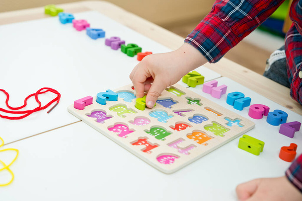 kid learning numbers through game. Sensory activity with wooden numbers and shoe laces. Educations at home, pre-school education, Montessori methodology. sequence of numbers, arithmetic problems. - Zdjęcie, obraz