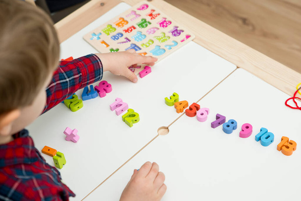 kid learning numbers through game. Sensory activity with wooden numbers and shoe laces. Educations at home, pre-school education, Montessori methodology. sequence of numbers, arithmetic problems. - Photo, Image