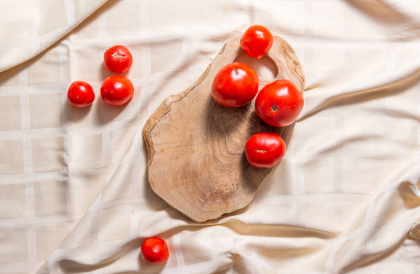 Oliivipuusta valmistettu leikkuulauta, jossa on neljä tomaattia. - Valokuva, kuva