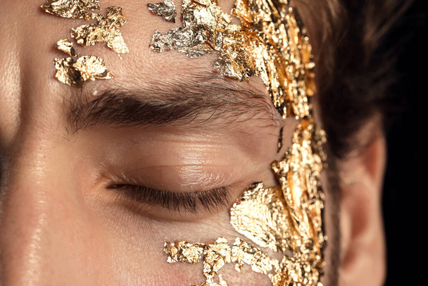 Handsome young man with golden foil on face, closeup - Fotoğraf, Görsel