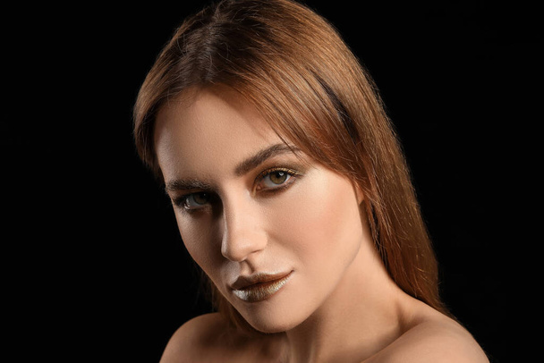Beautiful young woman with  golden makeup on black background - Foto, Bild