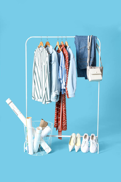 Rack met stijlvolle kleding, schoenen en accessoires op kleur achtergrond - Foto, afbeelding