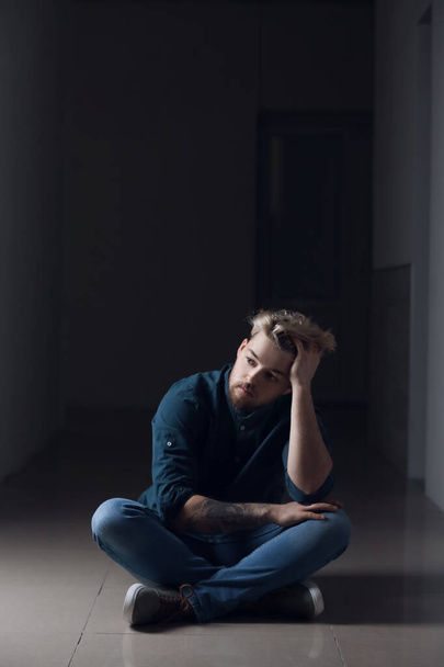 Депресивний молодий чоловік у темній кімнаті
 - Фото, зображення