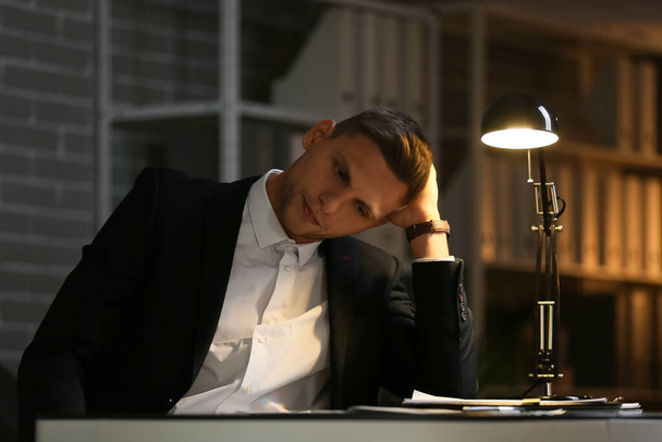 Депрессивный молодой бизнесмен в офисе поздно вечером - Фото, изображение