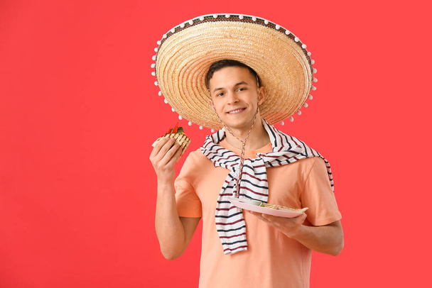 Jovem mexicano comendo quesadilla saboroso no fundo de cor - Foto, Imagem
