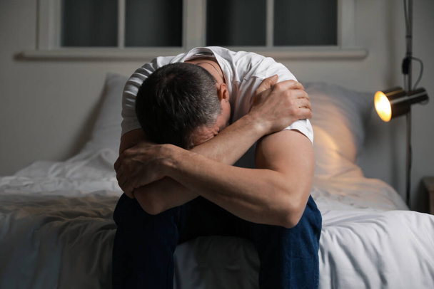 Депрессивный зрелый мужчина в спальне - Фото, изображение