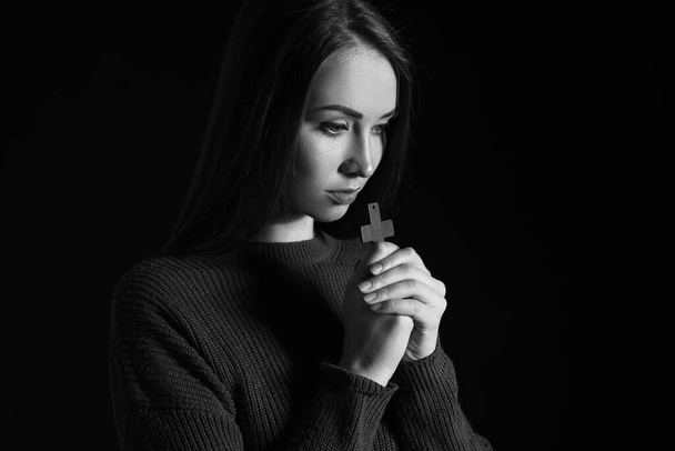 Black and white portrait of praying young woman on dark background - Foto, Imagen