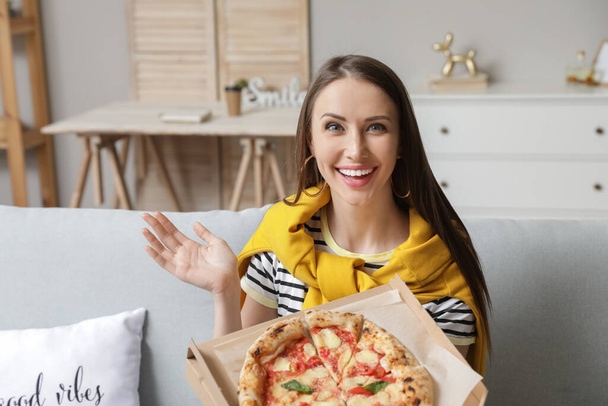 Beautiful young woman eating tasty pizza at home - Fotoğraf, Görsel