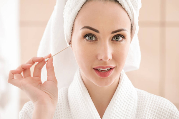 Mujer joven limpiando orejas con capullo de algodón en el baño - Foto, Imagen
