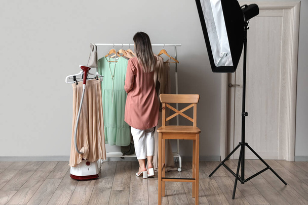 Жіночий стиліст вибирає одяг для зйомок у фотостудії
 - Фото, зображення