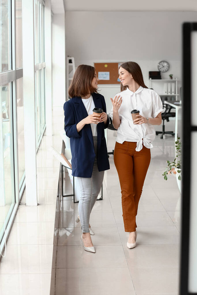 Female colleagues drinking coffee in office - Фото, зображення