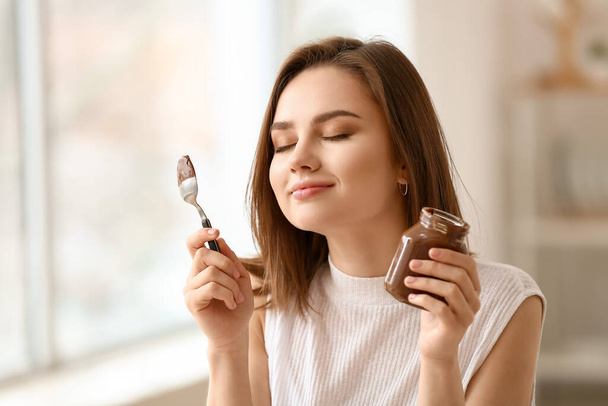 Beautiful young woman with tasty chocolate paste at home - Fotoğraf, Görsel