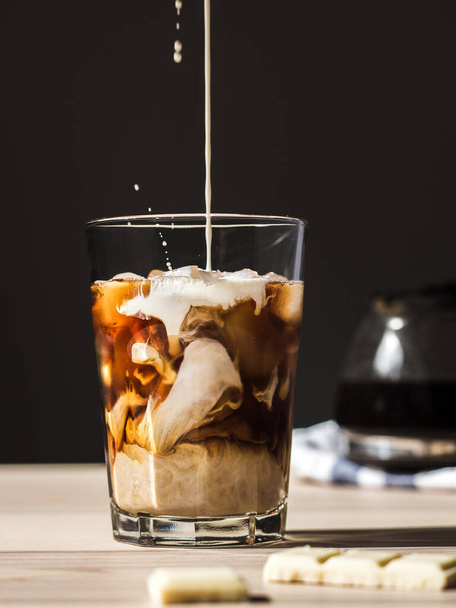лиття молока в чорну зварену каву в прозорому келиху зі сплесками
 - Фото, зображення