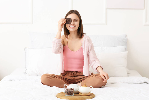 Красивая молодая женщина с вкусным шоколадом в спальне - Фото, изображение