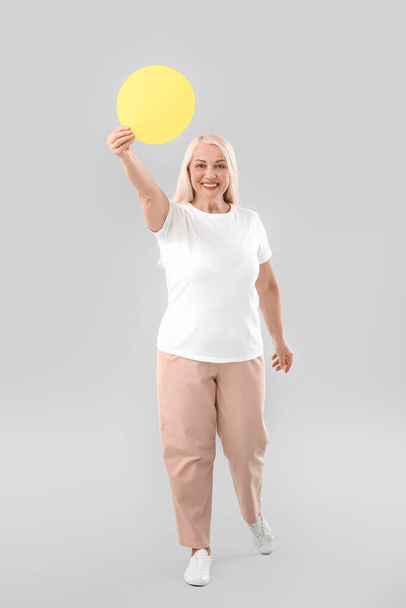 Ältere Frau mit leerem Papierblatt auf hellem Hintergrund - Foto, Bild