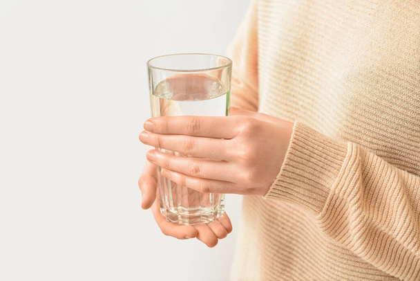 Žena se sklenicí vody na světlém pozadí - Fotografie, Obrázek