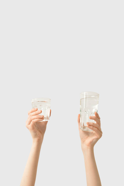 Female hands with glasses of water on light background - Zdjęcie, obraz