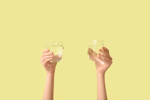 Female hands with glasses of water on color background - Foto, imagen
