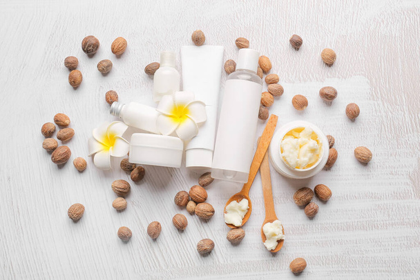 Pot de beurre de karité, noix et produits cosmétiques sur fond clair - Photo, image